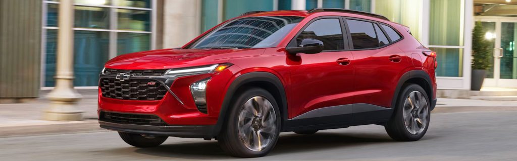 Red Chevrolet Trax driving on a city street.